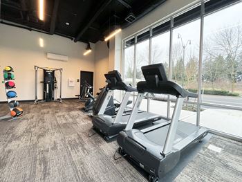 a gym with cardio equipment and a large window at The Duo, University Place, WA